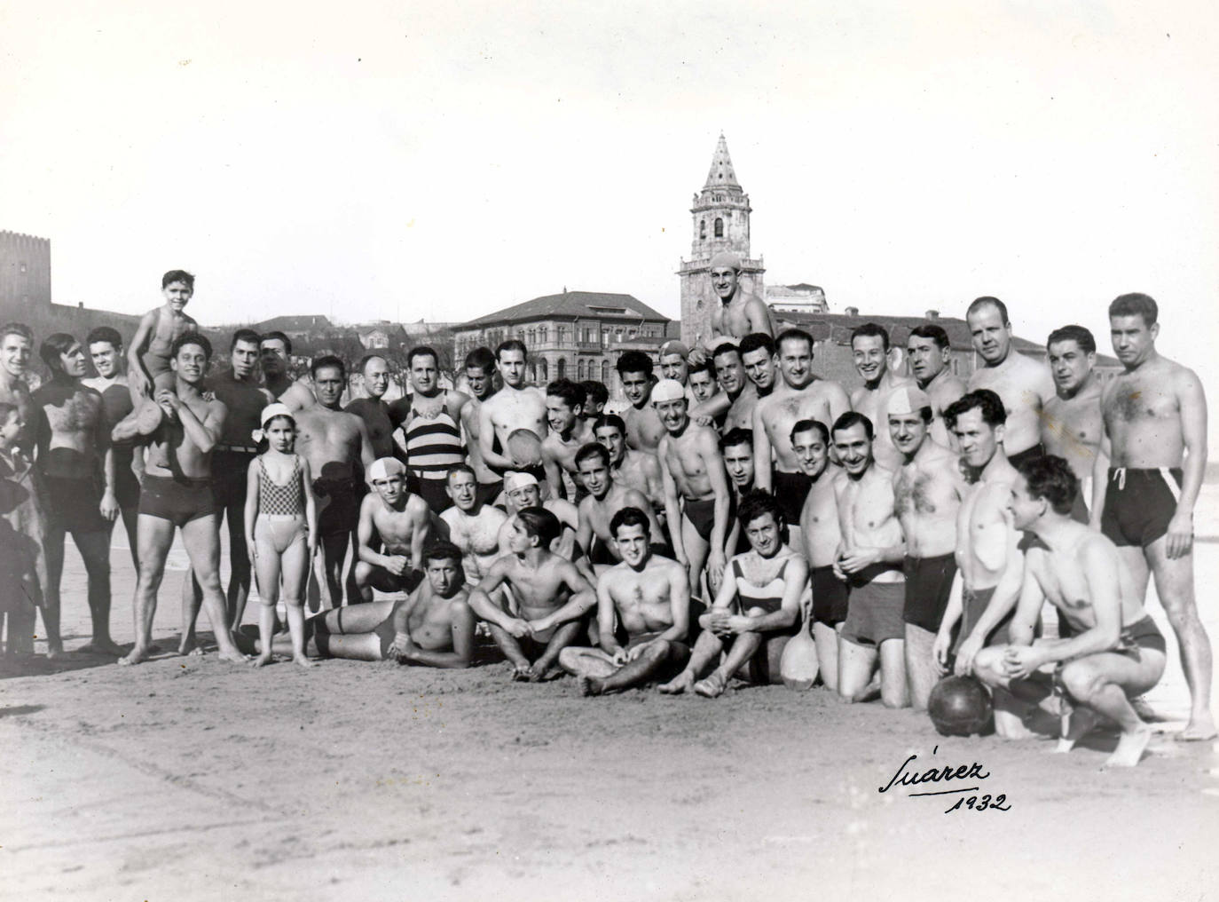 Bañistas en la Playa de San Lorenzo. Tras ellos la iglesia de San Pedro.