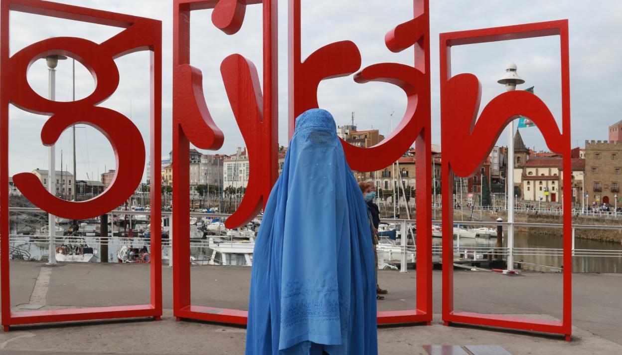 La activista gijonesa Antolina Gutiérrez posa junto a las letronas vestida con un burka, para denunciar la compleja situación a la que se enfrentan las mujeres afganas bajo el dominio del régimen talibán. 