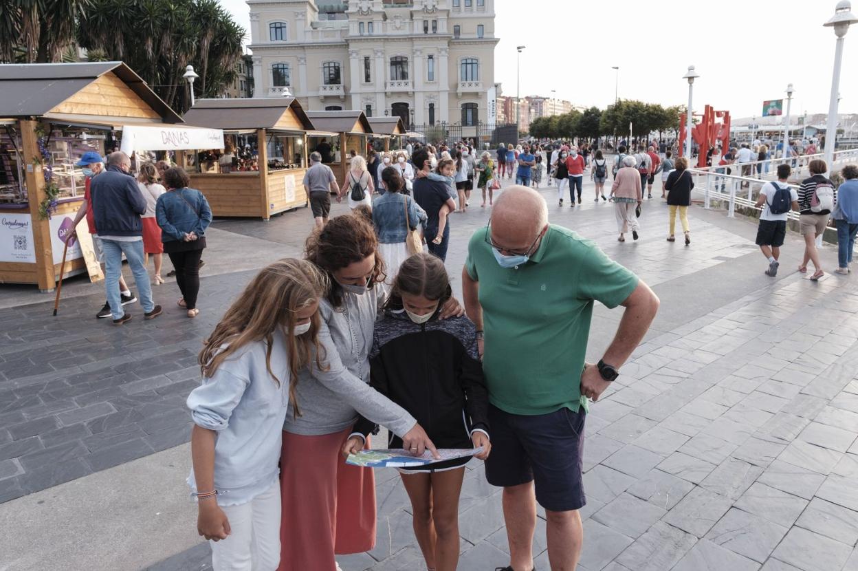 Unos turistas consultan un mapa de Gijón en la zona del puerto deportivo. 