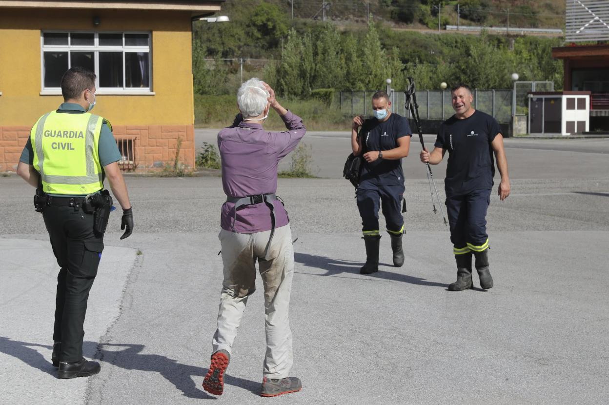 Los bomberos le entregan los bastones a la peregrina tras su rescate en Lena. 