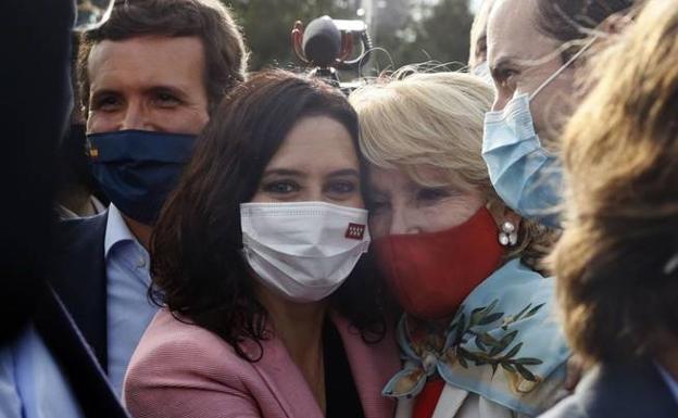 Ayuso y Aguirre se abrazan en un acto, con Pablo Casado al fondo. 