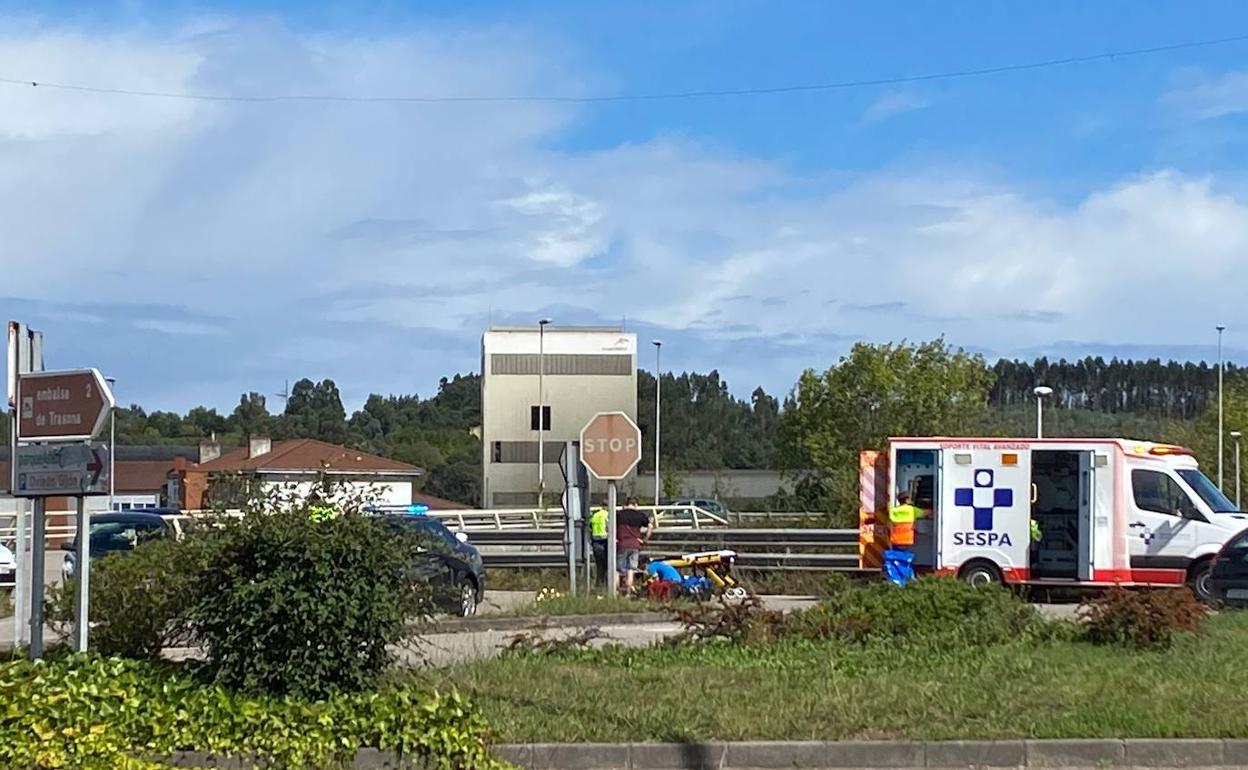 Una UVI móvil atiende al ciclista en la rotonda de acceso al centro comercial Parque Astur, en Corvera. 