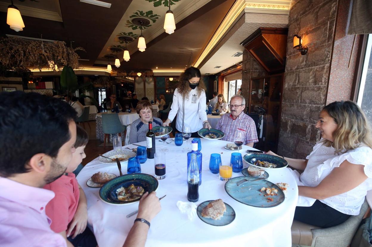 La familia Couchello Iglesias degustan el menú, mientras Lorena García les sirve los segundos platos. 