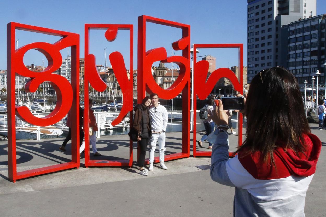 Gijón. Una joven toma una foto en las 'Letronas' a Andrea y Daniel, turistas de La Coruña. 