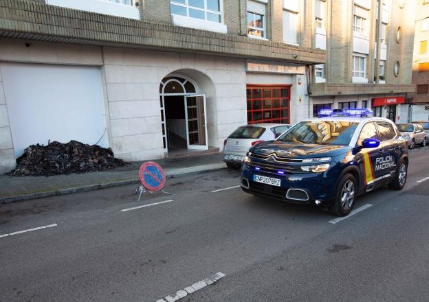 Una patrulla de la Policía Nacional, frente a los restos del incendio en el número 8 de la ca lle Faustino Vigil. 