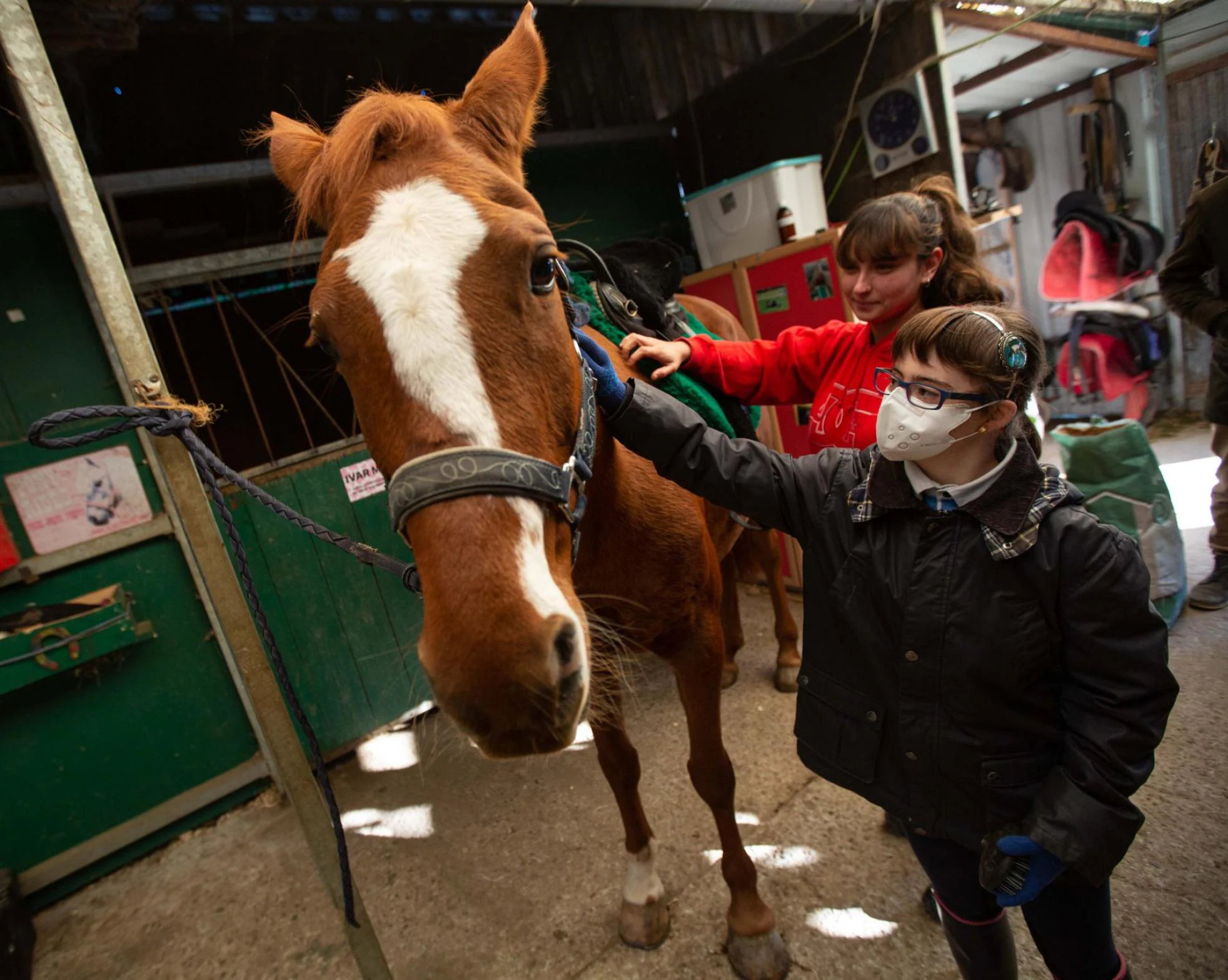 Sara Álvarez aprende a acariciar a los caballos con la ayudante de terapeuta Carla del Valle. 