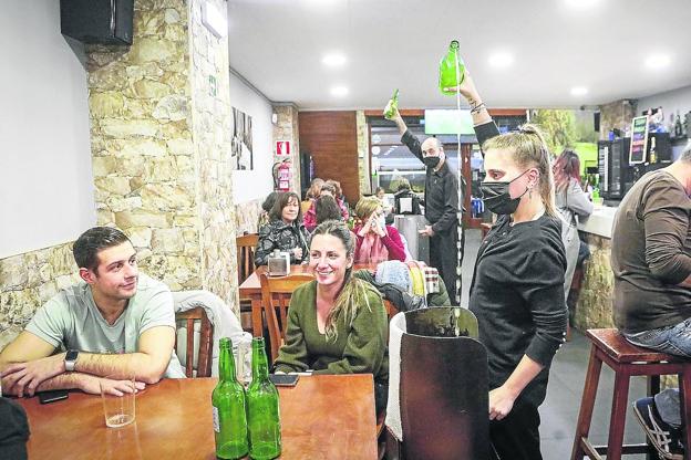 Una joven escancia una sidra en un establecimiento gijonés.