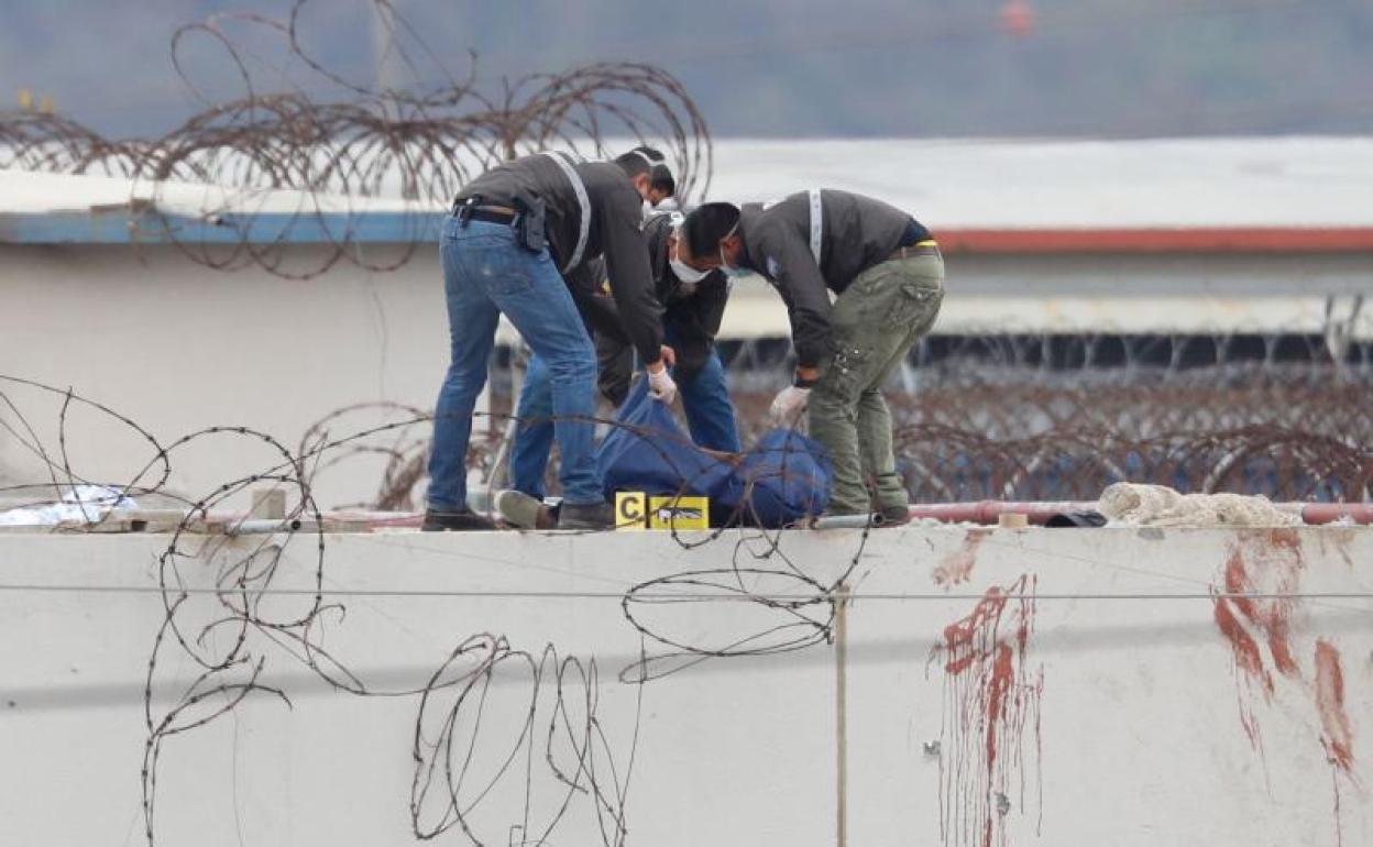 Policías retiran el cadáver de un preso en el techo de un pabellón de la Penitenciaría del Litoral en Guayaquil.