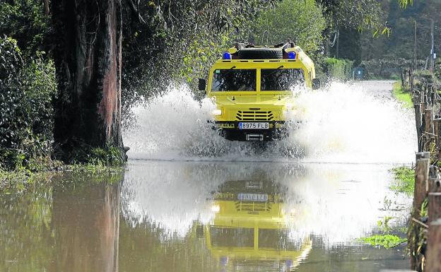 Bajo Nalón. Un vehículo de los bomberos atraviesa una zona anegada junto a una plantación. 