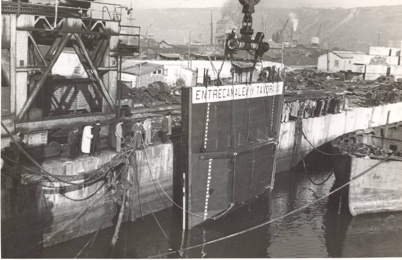 Puerta-barco para el dique seco: traslado desde el muelle de aíces (una vez emsabladas sus dos piezas) con la dársena de San Juan al fondo, a pleno rendimiento