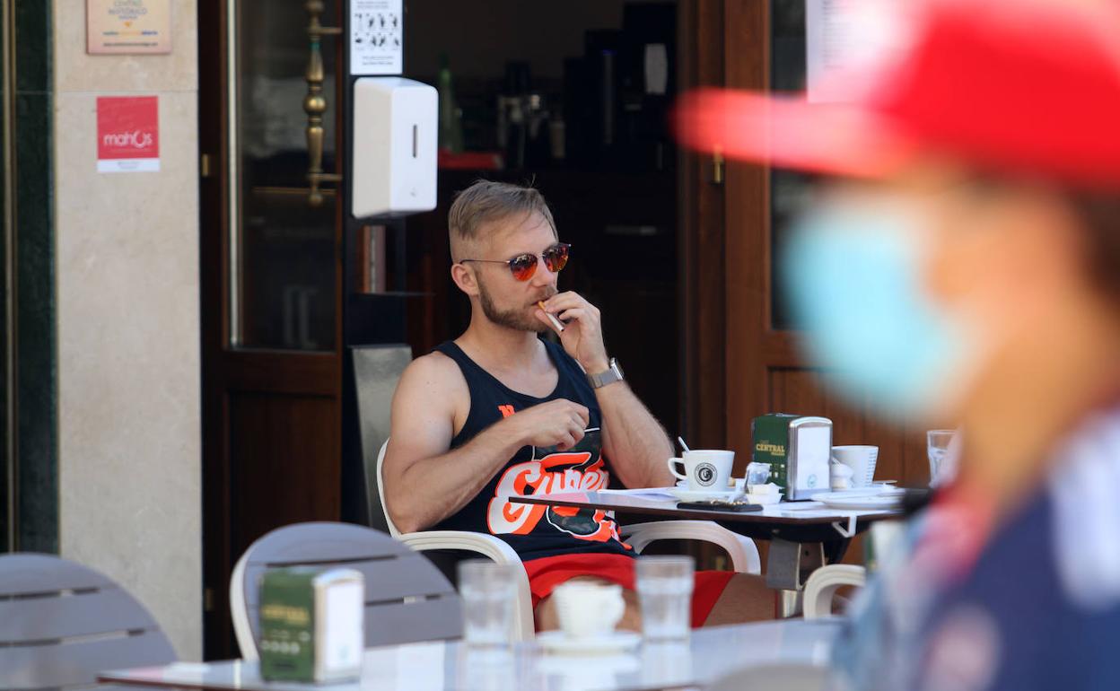 Un hombre fuma en la terraza de un bar.