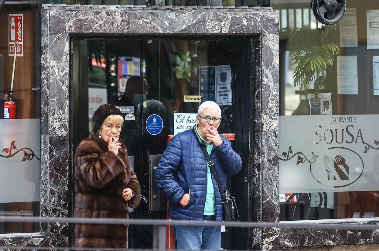 Dos mujeres fuman a la salida de un bar en Oviedo. 