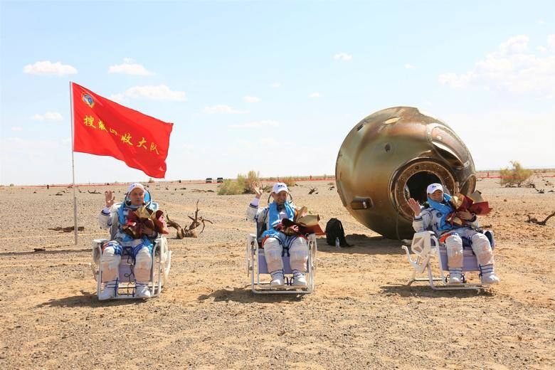 Los astronautas chinos Nie Haisheng (C), Liu Boming (R) y Tang Hongbo saludan frente a su cápsula de regreso después de su regreso a la tierra luego de la misión Shenzhou-12. China, el 17 de septiembre.