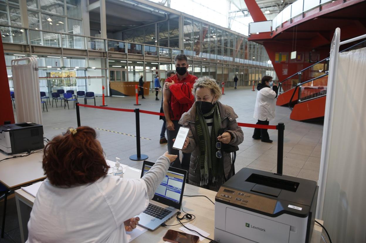 Una mujer da sus datos al personal administrativo del punto de vacunación del Palacio de Deportes de Gijón. 