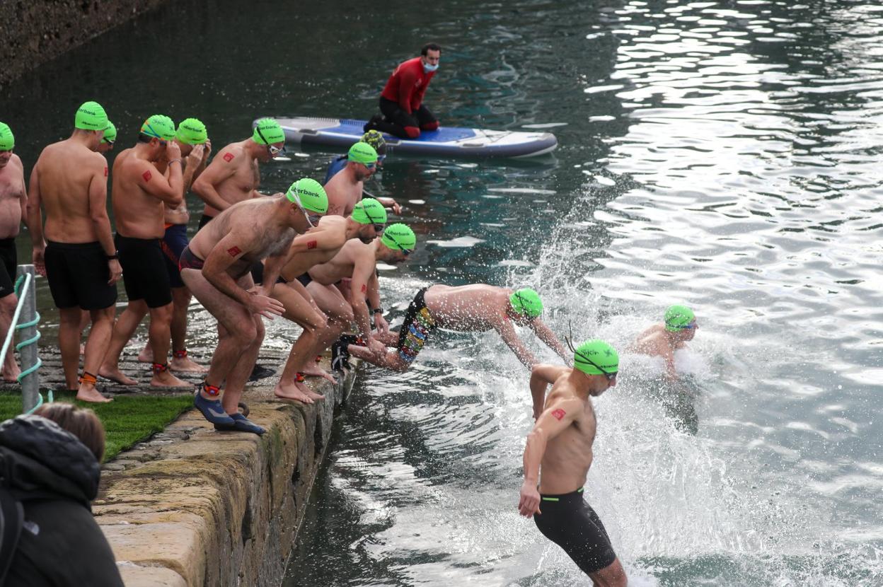 Los participantes de una de las tandas se zambullen en el Puerto Deportivo para iniciar la Travesía de Navidad. 