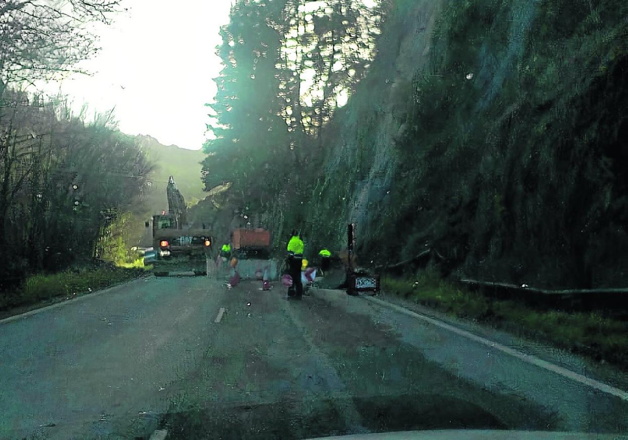 Varios operarios trabajando ayer en la carretera AS-15 para retirar el material desprendido. 