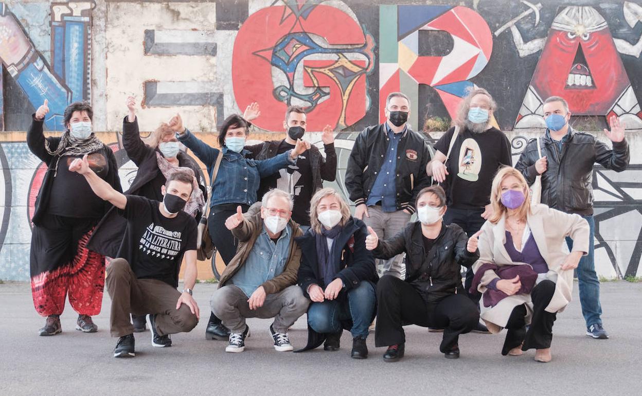 Parte del equipo que da forma a la Semana Negra, ante el grafiti realizado por el 'Mono' González en la entrada al recinto de los antiguos astilleros de Naval Gijón, uno de los lugares donde se celebró en los últimos años el festival literario.