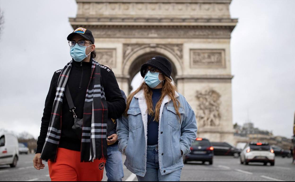 Una pareja pasea por París con la mascarilla puesta. 