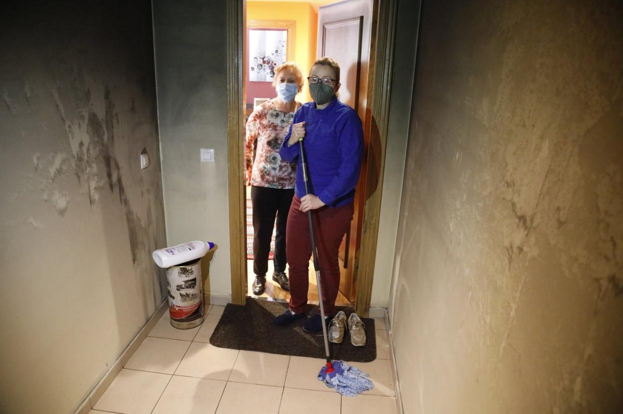 Lourdes Batista y su hija Isabel, vecinas, limpian los daños. 