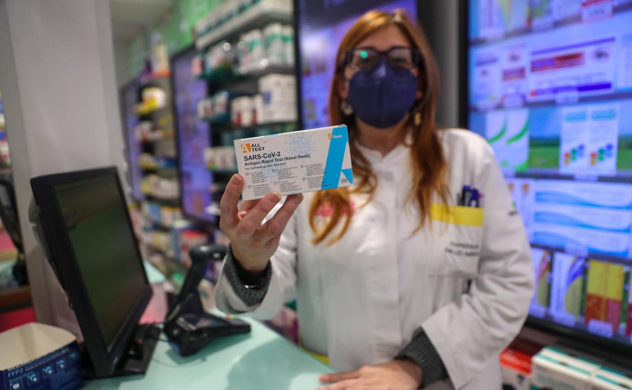 Una farmacéutica muestra un test de antígenos en una farmacia de Gijón. 
