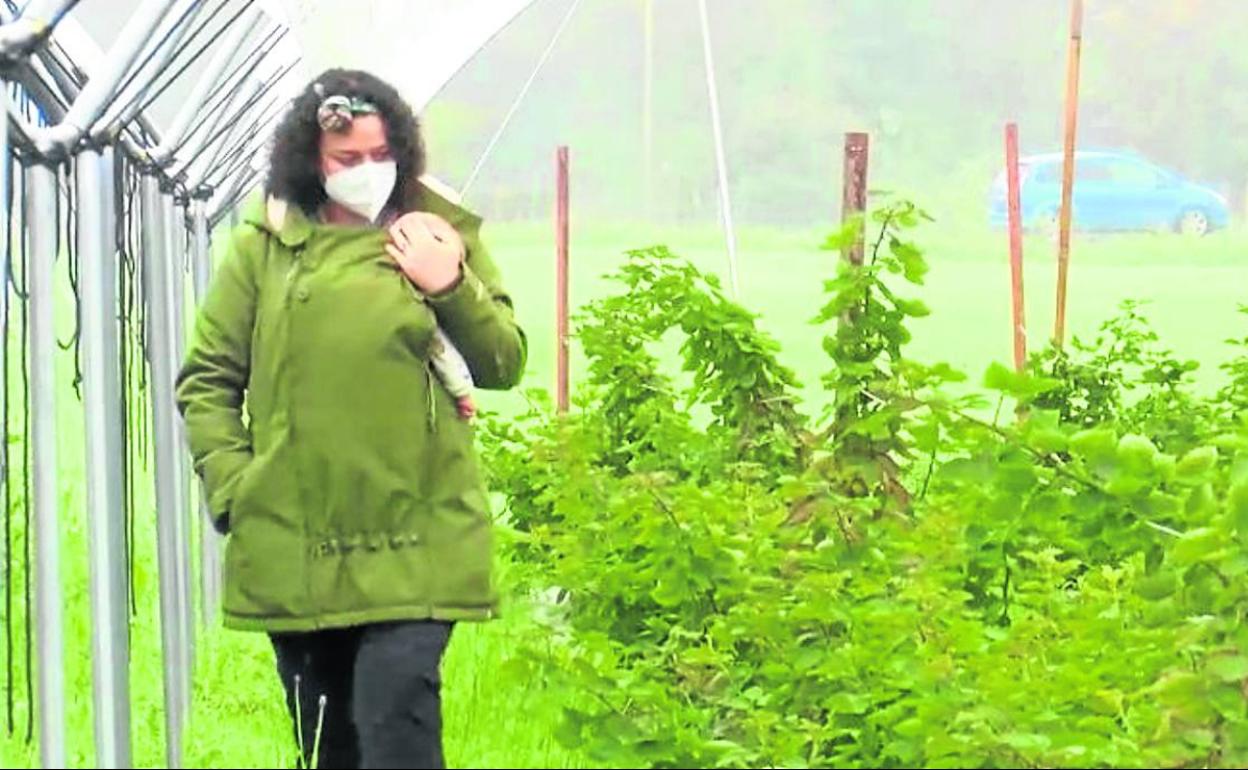 Alba Ortiz, en la plantación de moras que tiene en Colloto, con su pequeño en el regazo. 