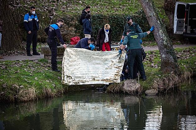Agentes de la Policía y de la Guardia Civil ayer, examinando el cadáver que apareció flotando en el río Nora, frente a la estación de tren. 