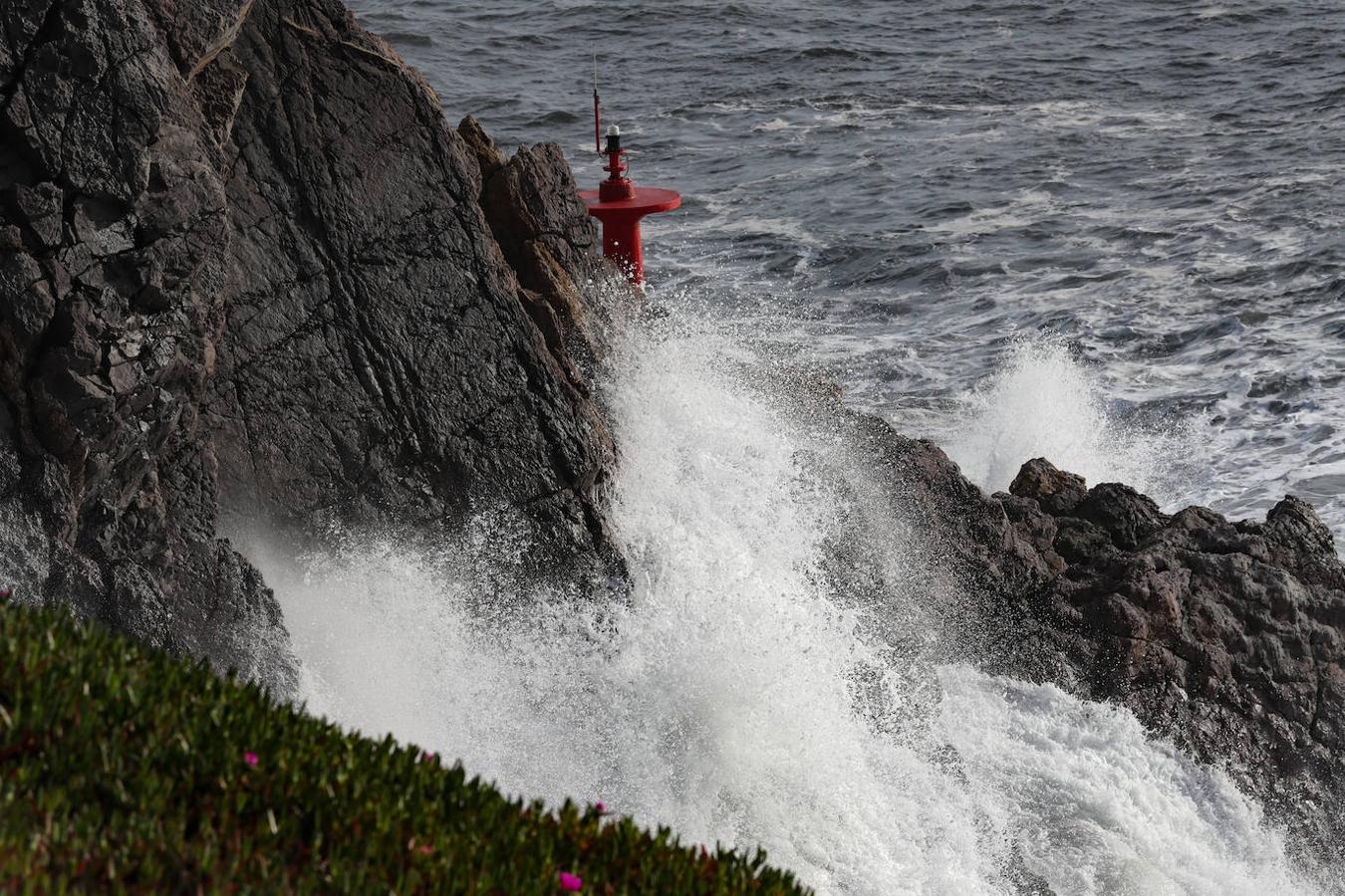 El faro de San Juan de Nieva estuvo rodeado de un fuerte oleaje durante la jornada de este jueves, en Avilés.