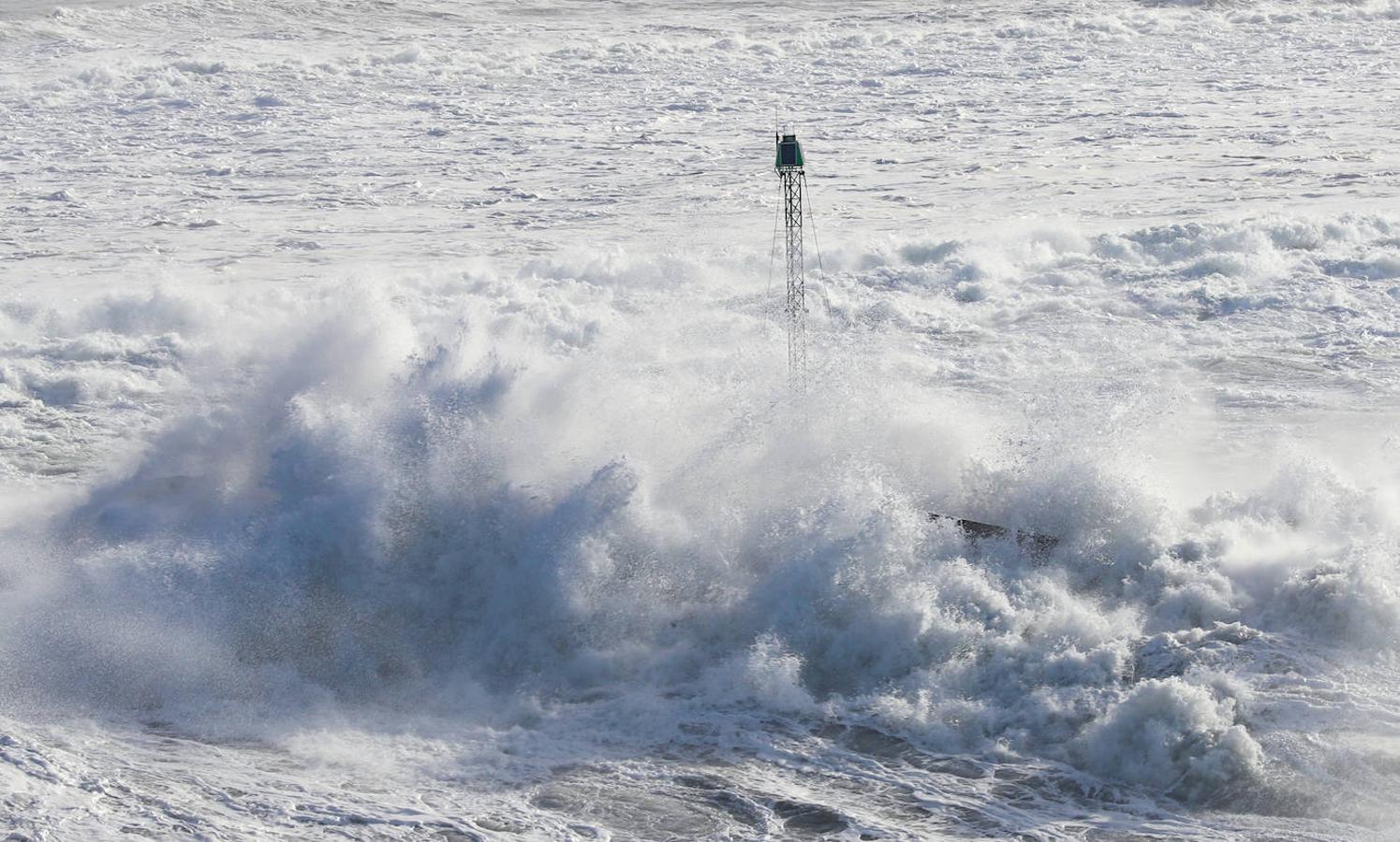 El faro de San Juan de Nieva estuvo rodeado de un fuerte oleaje durante la jornada de este jueves, en Avilés.