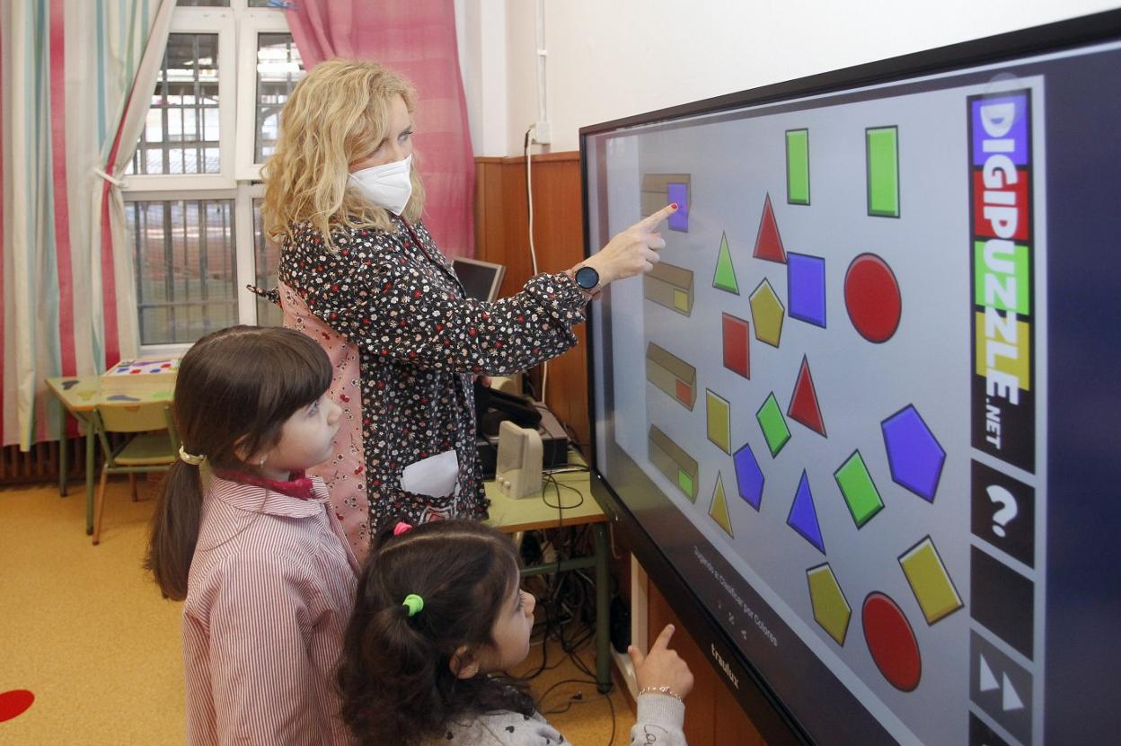 La tutora de los niños de cuatro años en el colegio Los Campos, Eugenia Velasco, junto a dos de sus alumnas, utilizando la pizarra electrónica. 