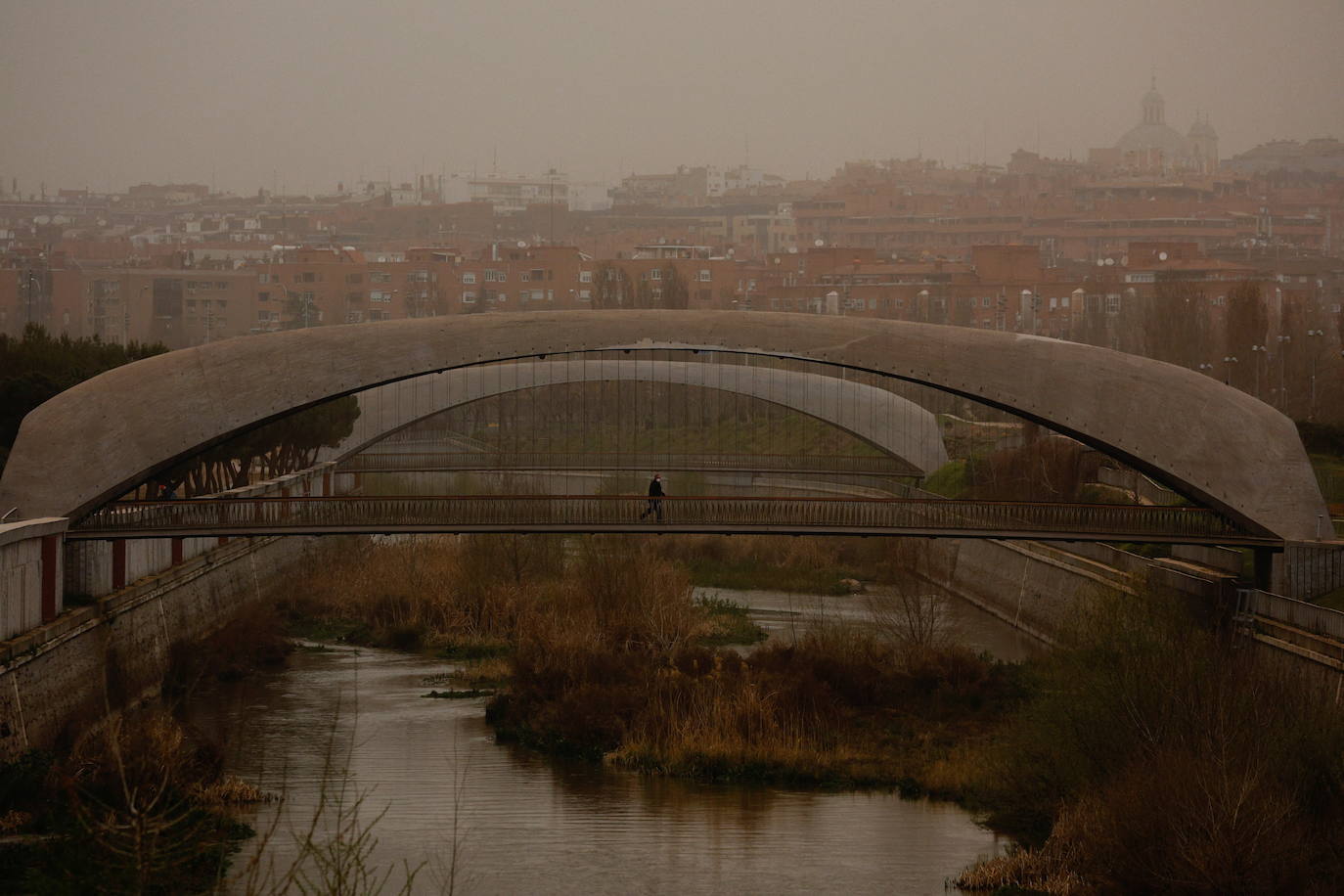 Una persona camina sobre uno de los puentes que cruzan el río Manzanares, en la zona conocida como Madrid Río.