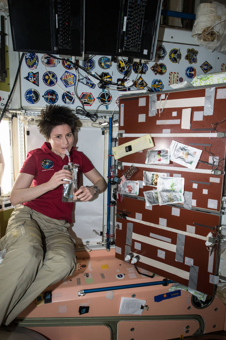 La astronauta de la ESA (Agencia Espacial Europea) Samantha Cristoforetti toma un trago en el módulo Unity de la Estación Espacial Internacional el 27 de abril 2015. La cocina de la tripulación se encuentra en este módulo, en el que se ven varios paquetes de comida a la derecha.