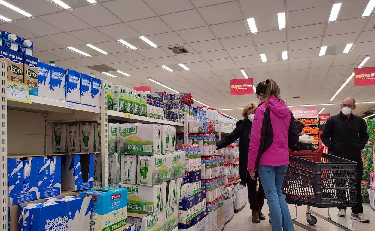 Varias personas hacen la compra en un supermercado.