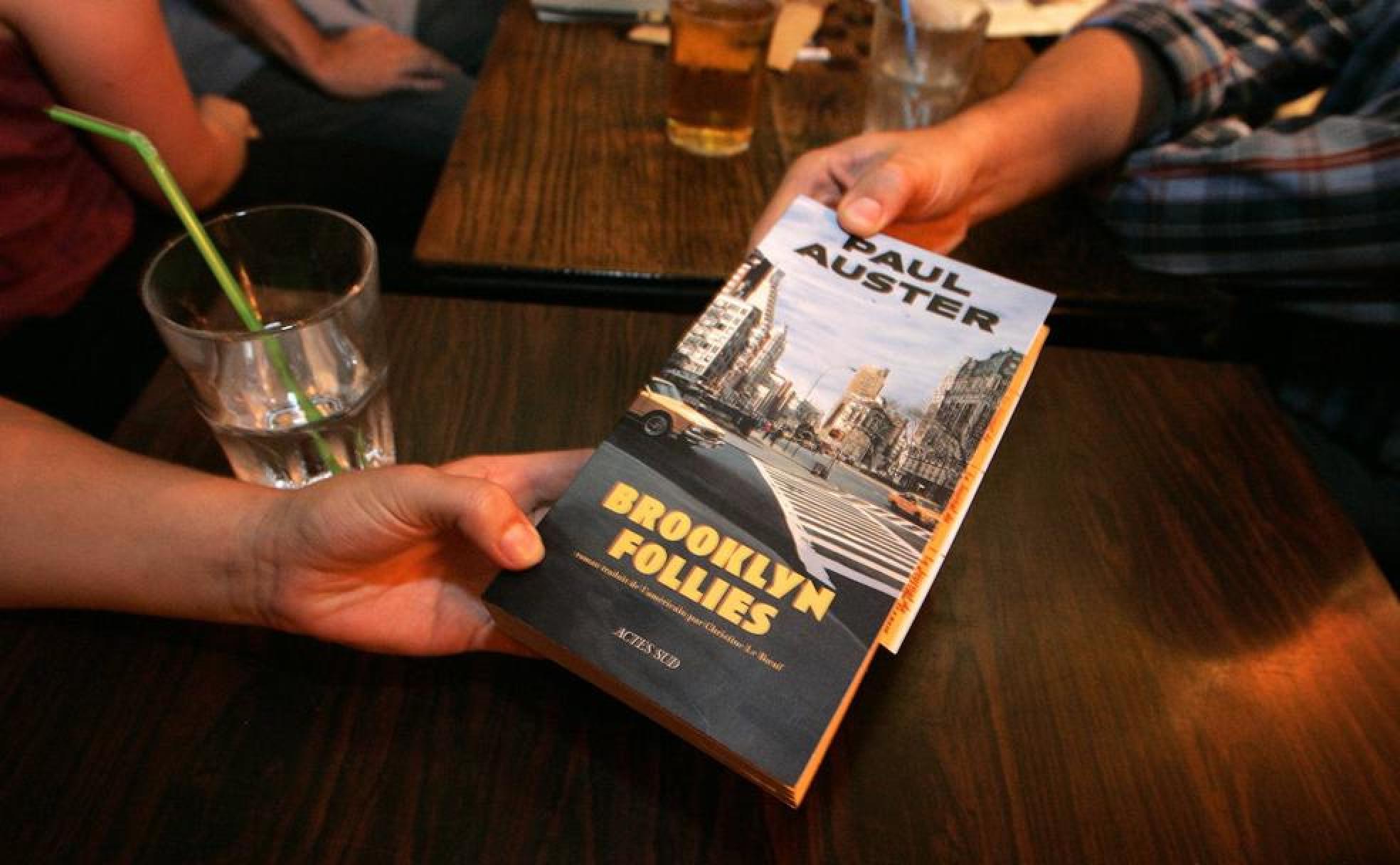 Dos lectores realizando 'Bookcrossing' con una novela de Paul Auster 