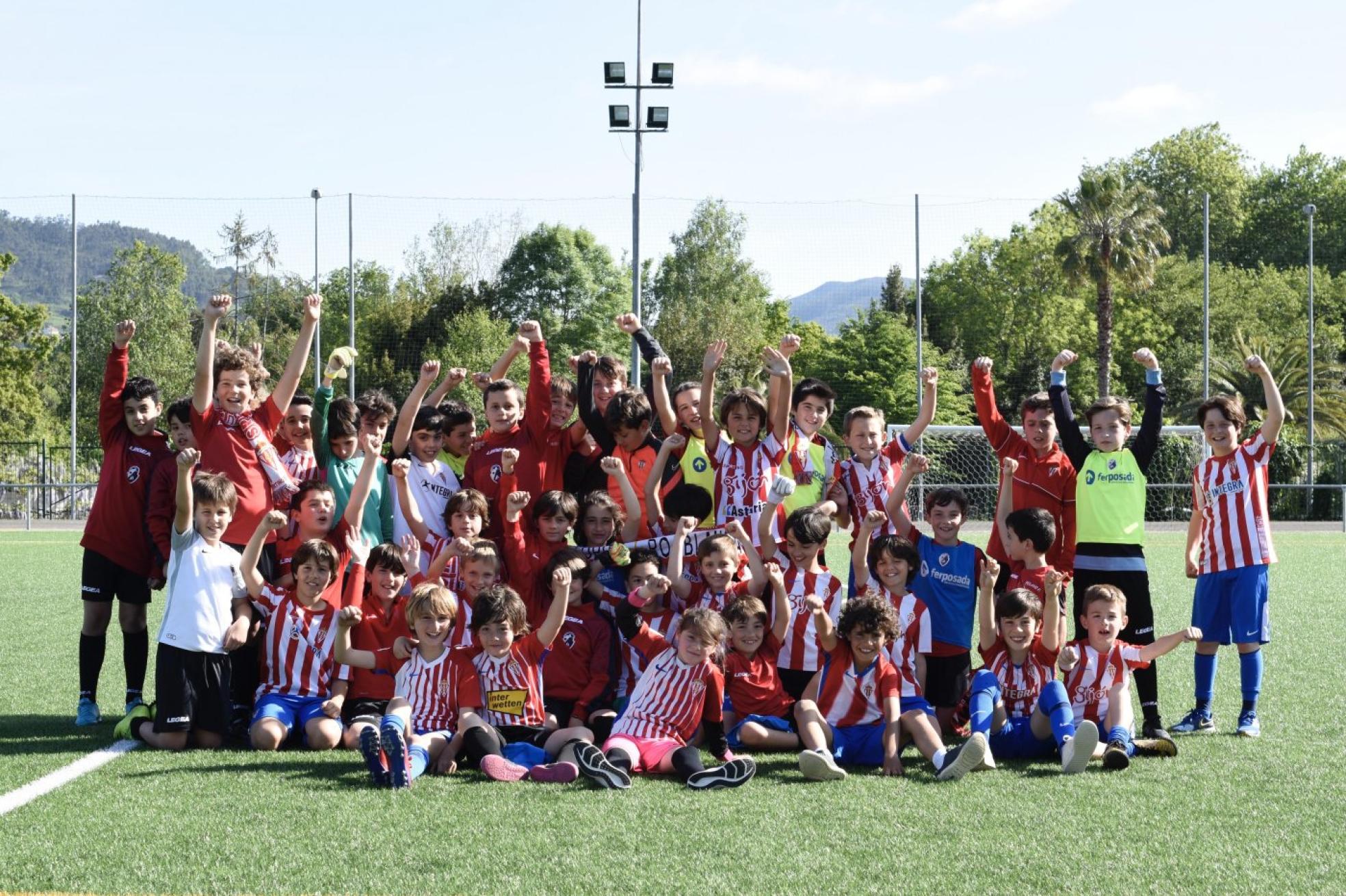 Jugadores de distintos equipos de La Asunción, con camisetas y bufandas del Sporting, en el campo de La Laboral. 