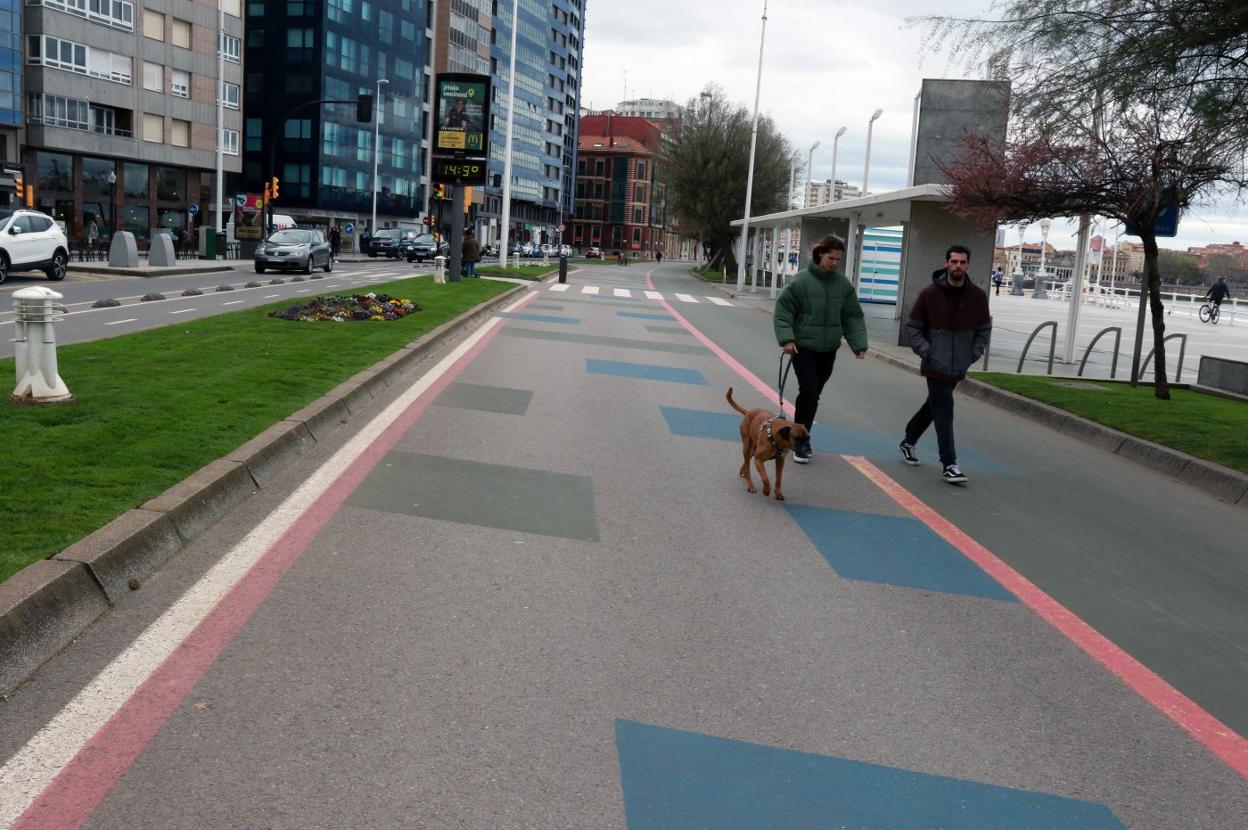 Una pareja paseando con su perro por el 'cascayu' del Muro, a la altura de la calle Ezcurdia. 