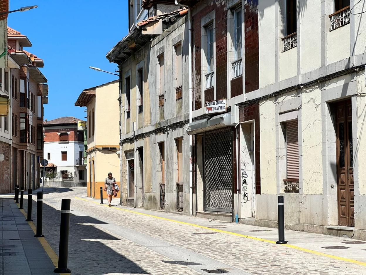 Una mujer pasea por Las Calles Nuevas de Grado, recientemente reasfaltada por el Ayuntamiento, que quiere darle un impulso comercial. 