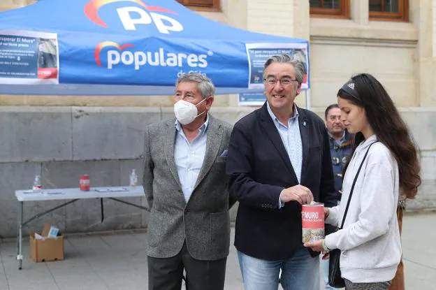 Pablo González, junto a Manuel Robledo, deposita un donativo en una de las huchas para Stop Muro.