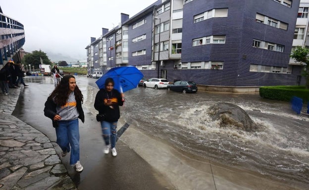 Dos jóvenes con la calle inundada en Ventanielles. 