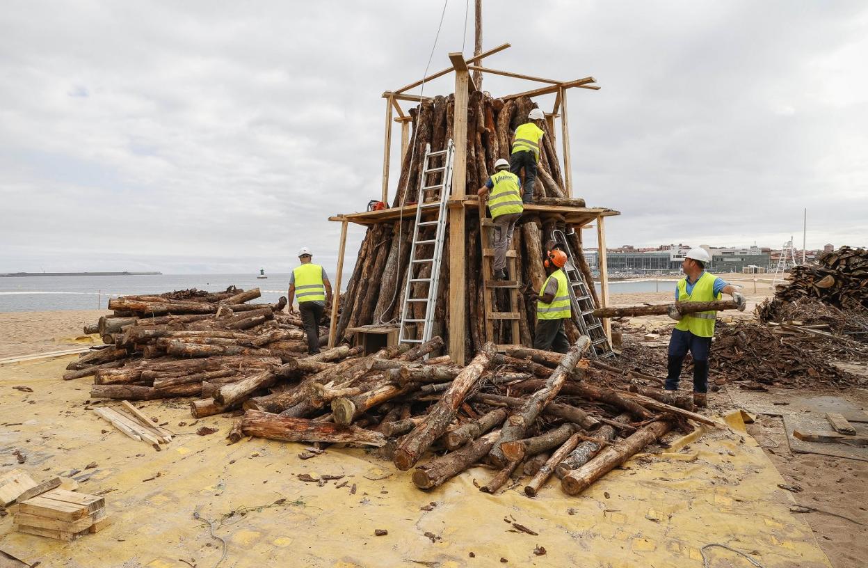 Varios operarios montando los maderos para la hoguera de Poniente. 