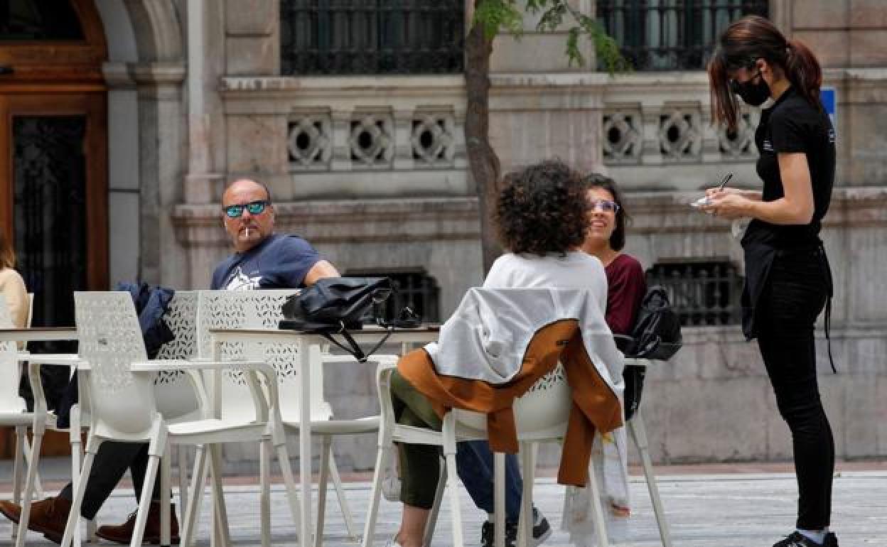 Una camarera atiende a unas clientas en un bar de Oviedo.