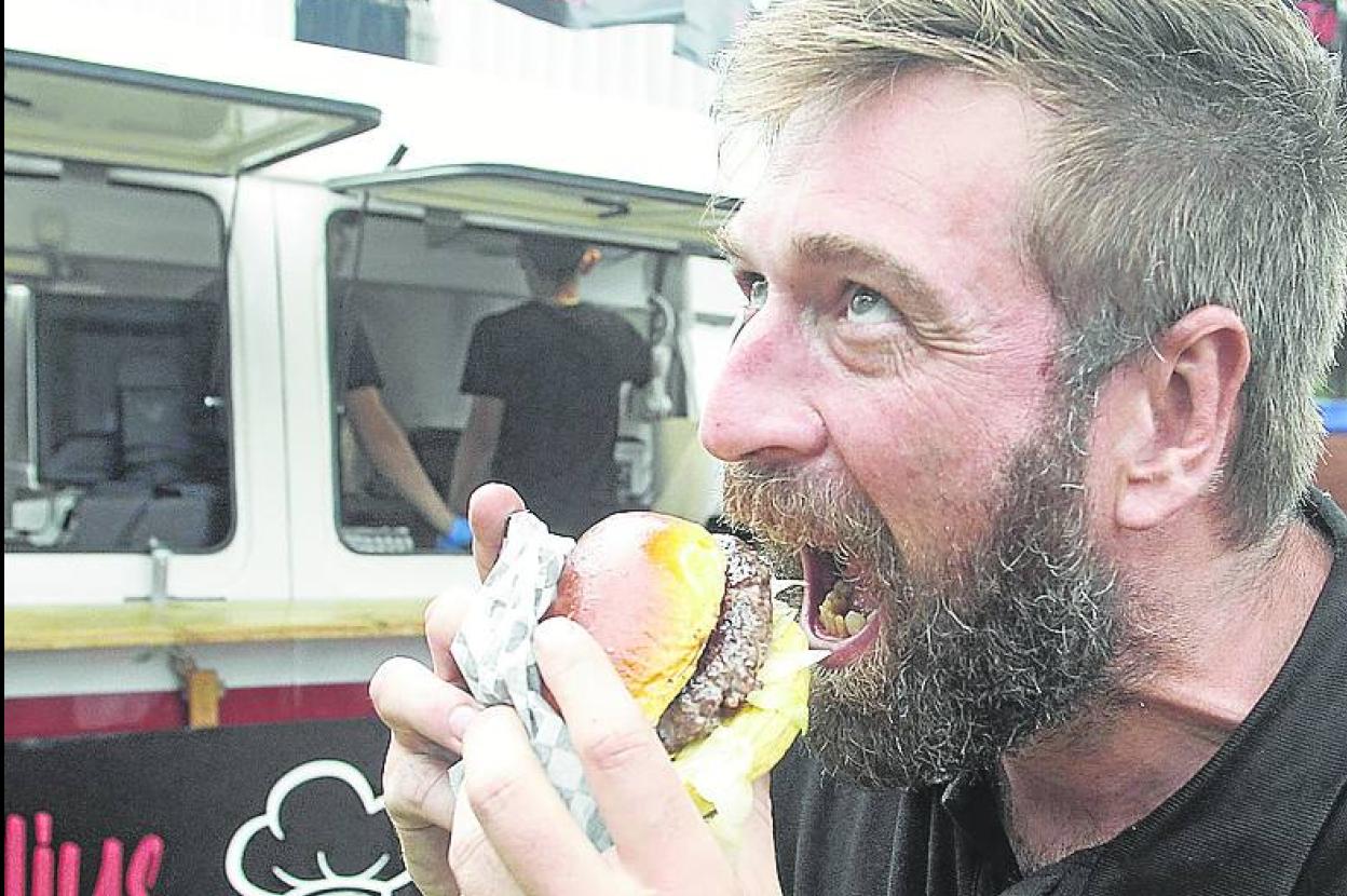 El mediático cocinero Julius Bienert, hincando el diente a una de sus hamburguesas solidarias.