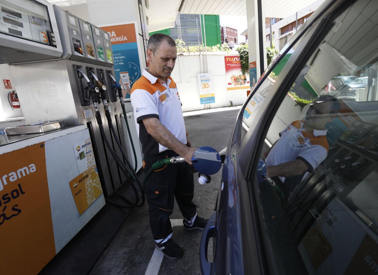 El empleado de una gasolinera echa combustible a un vehículo. 