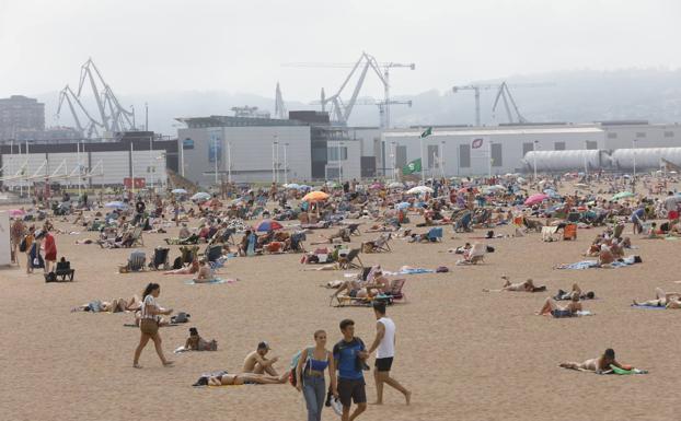 En la imagen, bañistas en Gijón. En el vídeo, los turistas disfrutan de las temperaturas de Asturias. 