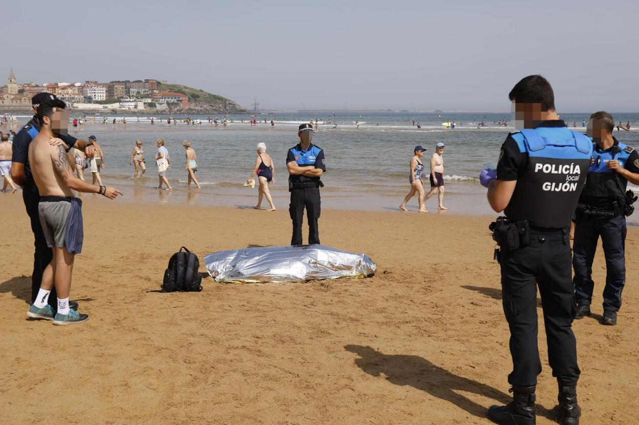 Agentes de la Policía Local y usuarios de la playa ante el cadáver del hamaquero de la Cocina Económica . 