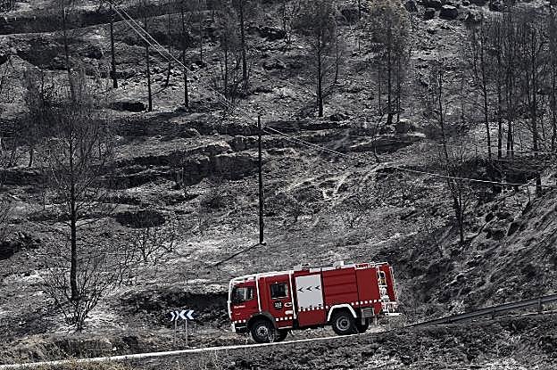 Un camión de bomberos circula por la superficie arrasada por el fuego en Pont de Vilomara, en Barcelona. 
