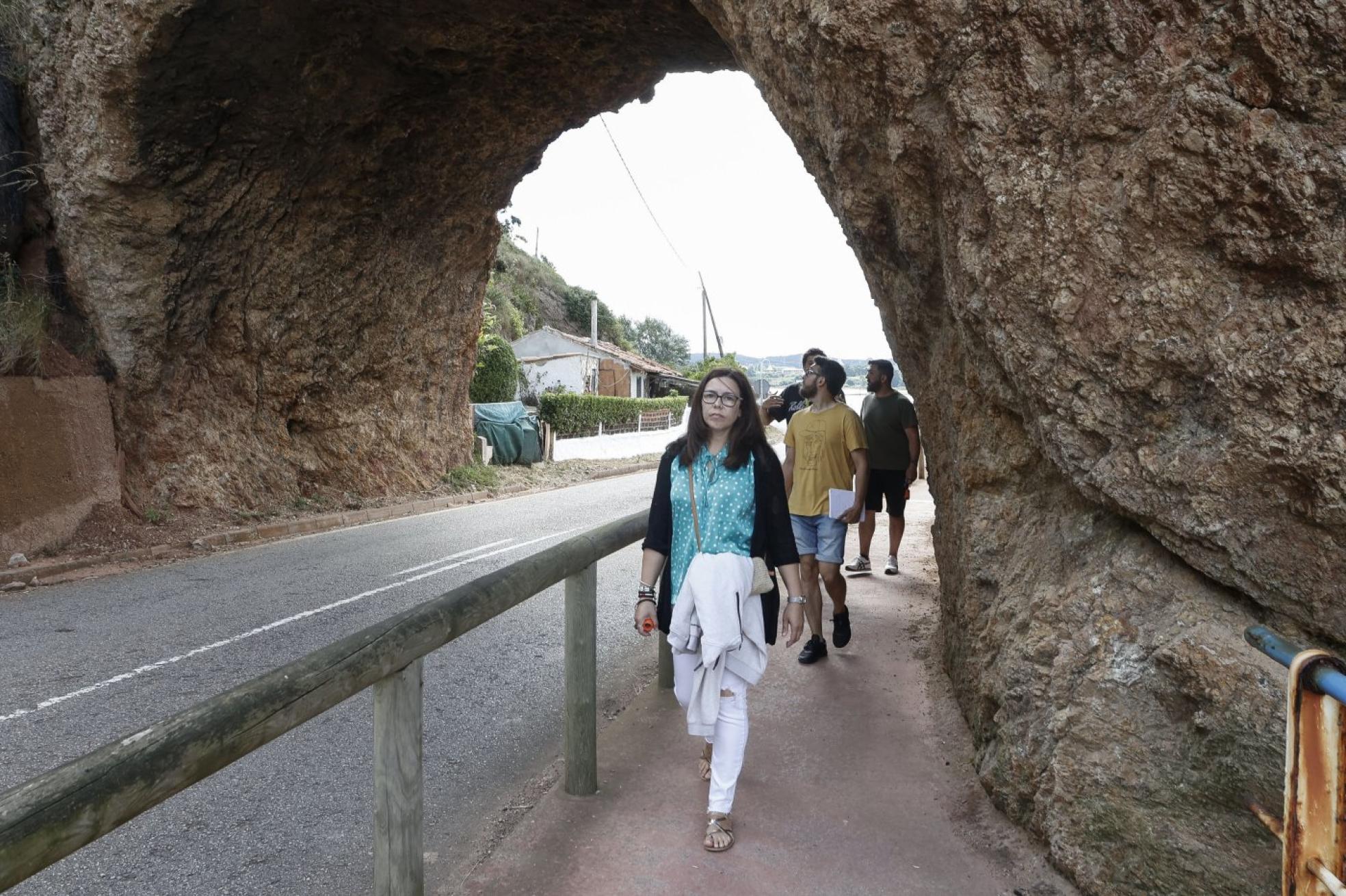 Ruta a pie. Un grupo de visitantes pasa por debajo de la 'Peña del caballo', en el paseo hasta el faro. 