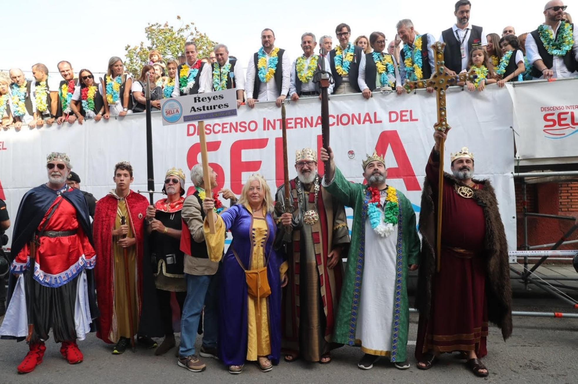 Los reyes astures, durante el desfile de Arriondas, ante la tribuna de autoridades. En la misma, entre otros, se puede ver de izquierda a derecha a Juan Cofiño (vicepresidente del Gobierno asturiano), José Manuel González Castro (alcalde de Cangas de Onís), Iván Allende (alcalde de Piloña) , Graciela Blanco (viceconsejera de Turismo), Noelia Macías (diputada socialista), Gimena Llamedo (secretaria de Organización de la FSA), Delia Losa (delegada del Gobierno en Asturias), Marcelino Marcos Líndez (presidente de la Junta General del Principado), Emilio García Longo (alcalde de Parres), Adrián Barbón (presidente de Asturias), Miguel Ángel Revilla (presidente de Cantabria), Salvador Illa (secretario general del PSE) y su mujer Marta Estruch, Juan Manuel Feliz (presidente del Codis) y Raúl Entrerríos (pregonero). También estaba en la tribuna el alcalde de Ribadesella, Ramón Canal. 