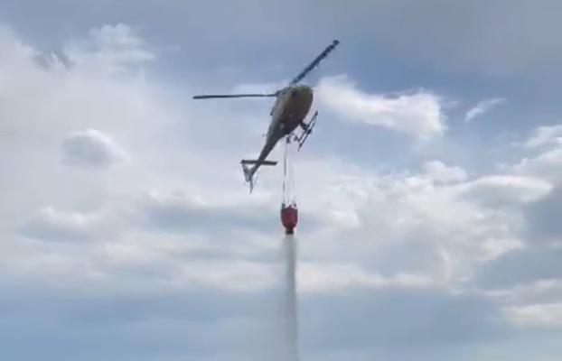 El helicóptero de Bomberos de Asturias lanza agua para sofocar uno de los incendios del occidente