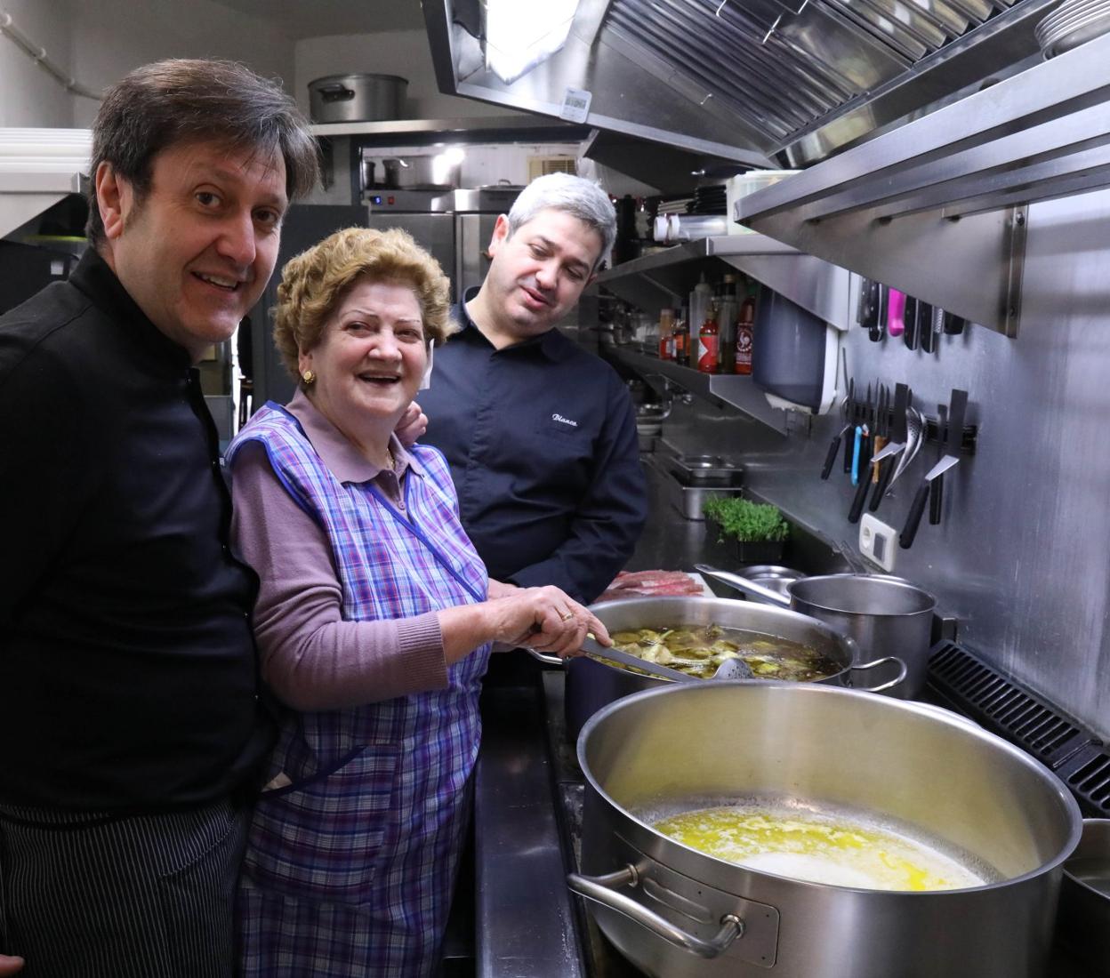 Pepe y Enrique Ron, con su madre, Engracia Line, en la cocina del restaurante cangués.