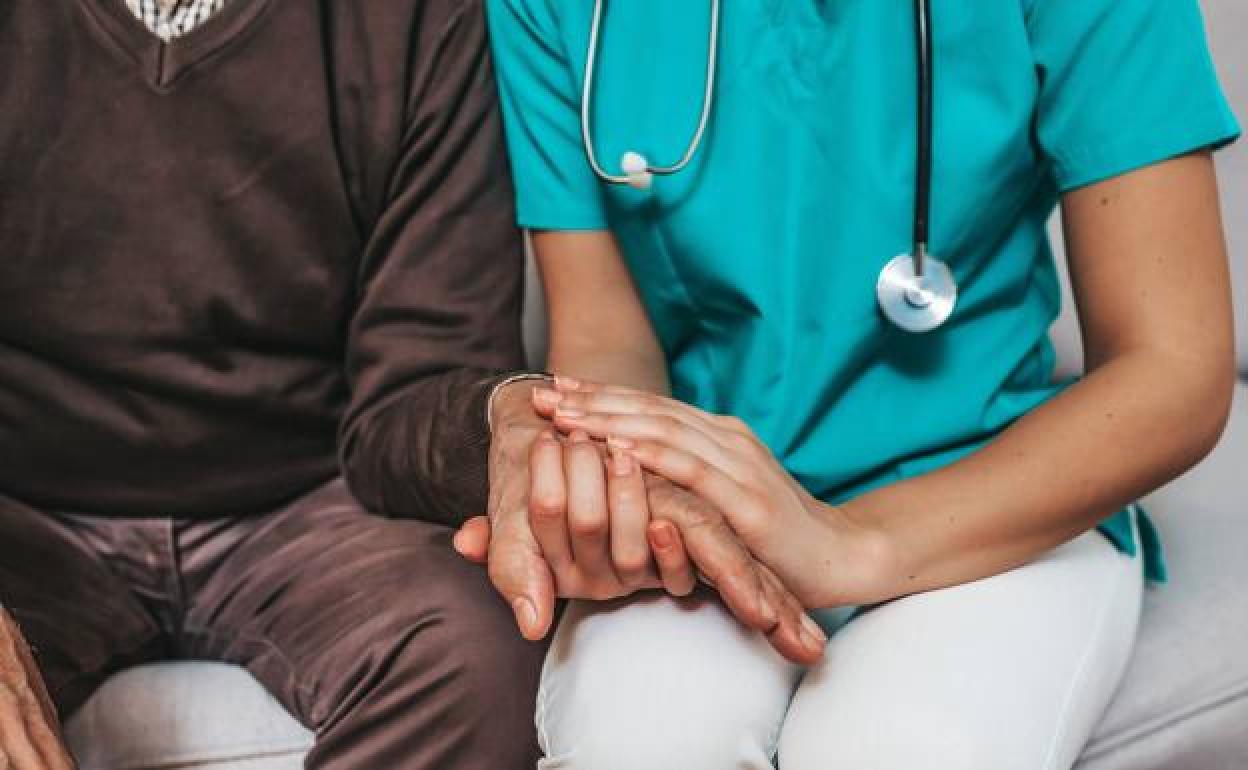 Un enfermo de alzhéimer acompañado por una sanitaria 